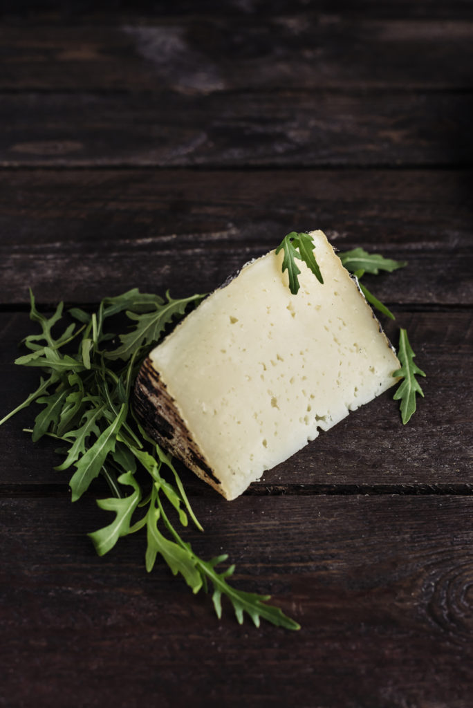  Manchego. Manchego ist ein spanischer gereifter Käse, der aus Schafsmilch von Tieren hergestellt wird, die auf den berühmten spanischen Ebenen weiden. Er hat eine harte Haut mit einer ungewöhnlichen graubraunen Farbe und einem cremeweißen Inneren. Der Geschmack ist mild mit einem charakteristischen Nachgeschmack von Schafsmilch, was gut zur salzigen Note passt. In Spanien zählt er zu den beliebtesten und meist ins Ausland exportierten Käsesorten. Traditionell wird er mit Birnenmarmelade serviert, die den würzigen Nachgeschmack stark bricht. Manchego kommt in drei Varianten vor: Fresco (junger Käse, Reifezeit 50 Tage), Viejo (reifer Käse) und Curado (alter Käse, der sogar 3 Monate gealtert wird), von denen sehr reifer Käse die Farbe erheblich verändert, die grau wird. Damit ändert sich der Geschmack des Käses und erlangt Schärfe. Manchego schmeckt als Snack oder Beilage mit Brot oder als Beilage für Salate. Er eignet sich gut für warme Gerichte, zum Beispiel in gebackenen Nudeln mit Chorizo oder Kichererbsen in Tomaten. Sie können damit köstliche Spießchen machen oder ihn mit getrockneten Tomaten servieren. Manchego ist ein kulinarisches Symbol für Spanien. Dieser Käse passt gut zu getrockneten Tomaten, Schinken, Oliven und frischem Brot. Manchmal wird er in Olivenöl mariniert, wodurch er etwas dunkler wird. Beliebte Rezepte mit Manchego sind vor allem Salate aller Art. Er wird auch als Snack mit Quitten, Granatapfel oder Nüssen serviert. Oft enthalten Gerichte mit Manchego auch Jamon und daher auch spanischen Parmaschinken. Sie werden meistens in Verbindung mit einem Glas Rotwein serviert, der etwas stärker ist. Manchego zeichnet sich durch seinen intensiven Geschmack und sein Aroma aus. Je älter der Käse ist, desto intensiver und schärfer ist sein Geschmack. Er ist ein klassischer Tafelkäse. Gerichte mit Manchego können sowohl als Vorspeise als auch als Hauptgericht serviert werden. 
 